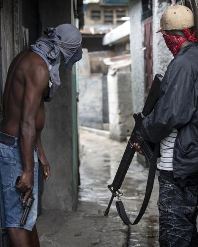 Two gang members stand armed with a revolver and a rifle in a narrow alley in Port-au-Prince, the capital of Haiti.